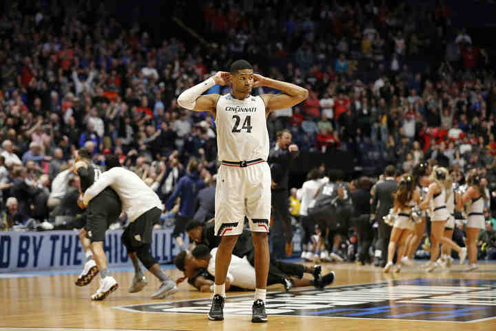 Cincinnati Bearcats forward Kyle Washington (24) walks off the court as the Nevada Wolf Pack celebrates on the floor after the final buzzer of their NCAA second round game at Bridgestone Arena in Nashville. The second-seeded Bearcats were eliminated from the tournament by the Wolf Pack with a 75-73 loss.    (Sam Greene / The Cincinnati Enquirer)